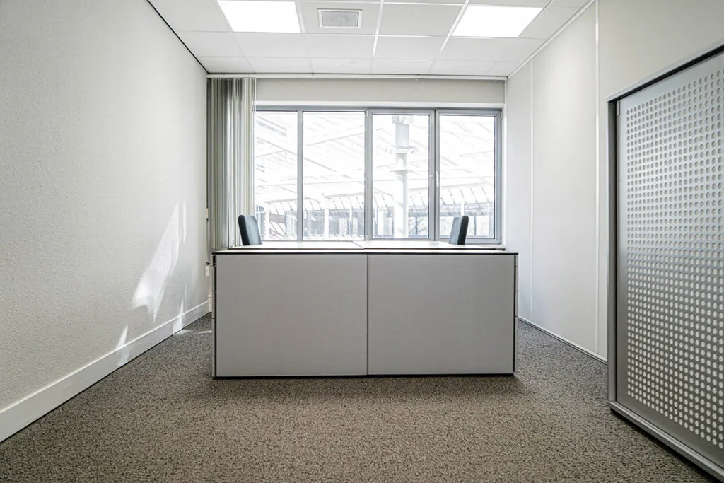 Licht, modern kantoor met twee bureaustoelen en een groot raam aan de Burgemeester van Karnebeeklaan.